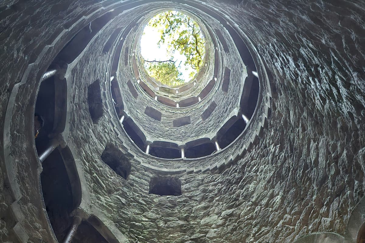 The Initiation Well at Quinta da Regaleira, Sintra — a 27-metre spiral staircase descending into the earth through nine landings lit by daylight from above